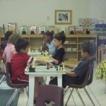 Children gathered on table sitting together to play chess