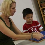 A teacher and little boy is doing hands on project