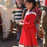 A girl standing among other students wearing a red frock