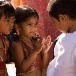 Two Indian girl clapping looking a boy wearing white kurta